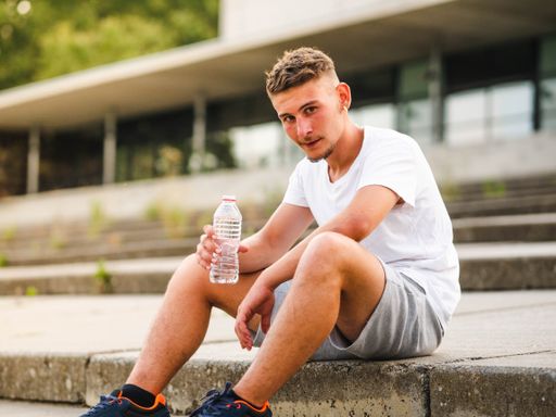 A young attractive sportsman drinking water after training - sport concept
