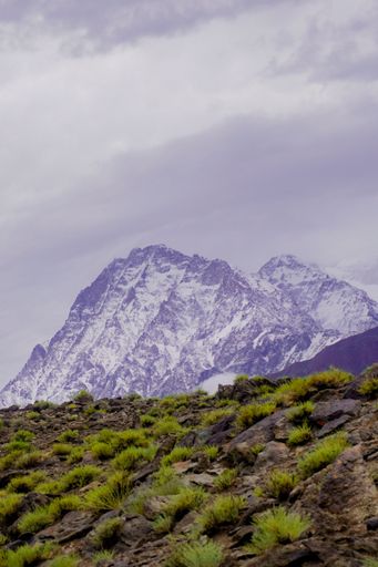 A vertical shot of snowy mountains against the background of the cloudy sky.