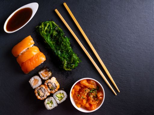 A closeup shot of sushi rolls with fried greens on a black surface