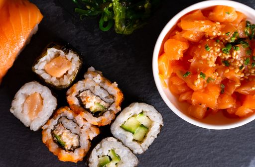 A closeup shot of sushi rolls with fried greens on a black surface