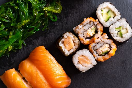 A closeup shot of sushi rolls with fried greens on a black surface
