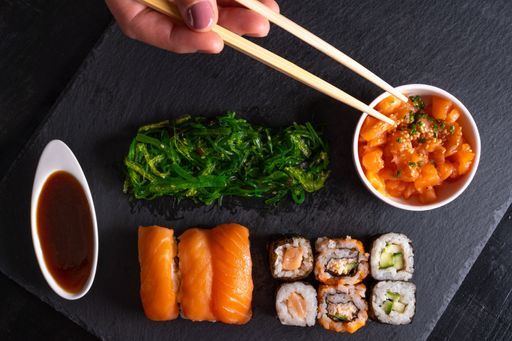 A closeup shot of sushi rolls with fried greens on a black surface