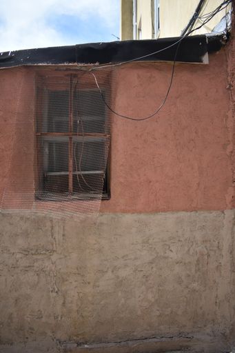 A vertical shot of a colored old house wall with a window