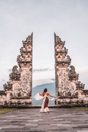 A vertical shot of a female in sarong climbing the Lempuyang Temple stairs of Bali