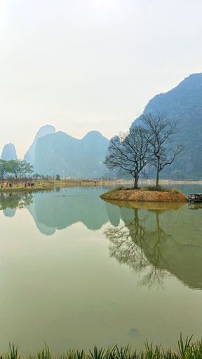 A vertical shot of a small lake with the Guilin mountains on the background