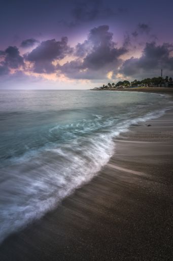 A scenic vertical shot of a seashore during twilight with the waves having a misty water effect