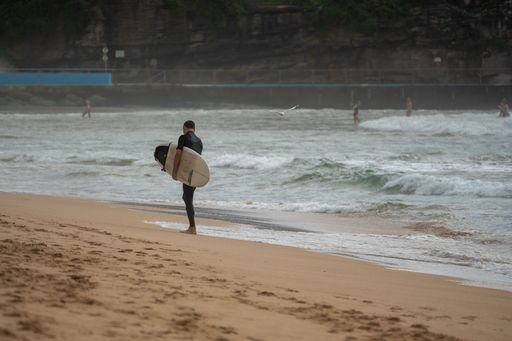 A surfer with a board standing on the shore. Manly Beach. Australia.