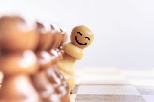 A chess piece on a board peeking out with a smiley face