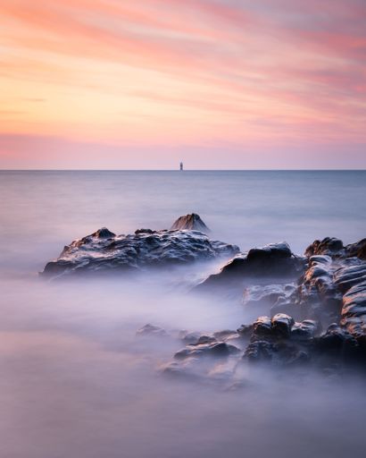 A vertical long exposure shot of the seascape in Guernsey during a sunset