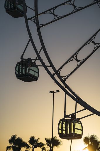 A vertical shot of cabins of a Ferris wheel in the city at sunset