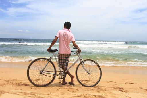 The view of a cyclist standing on the sand enjoying the sea waves