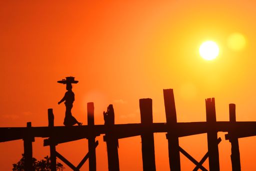 The silhouette of a cowboy figurine on the fence before the orange sky