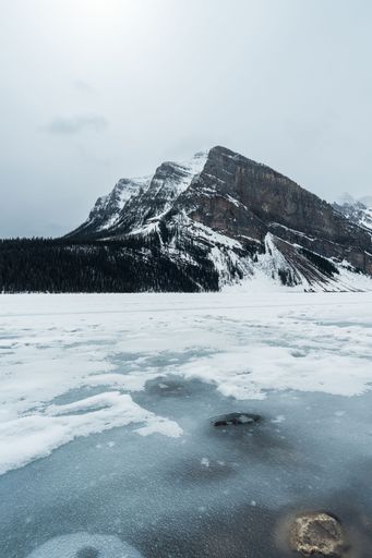 A vertical shot of the frozen lake near snowy mountains in Jasper, Canada