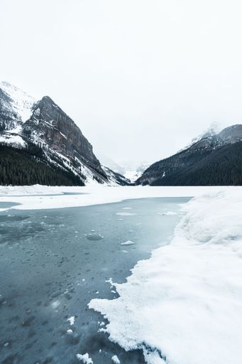 A vertical shot of the frozen lake near snowy mountains in Jasper, Canada