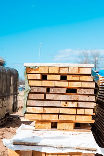 A vertical shot of a pile of wooden planks on a construction site