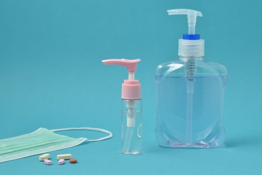 A closeup shot of bottles of hand sanitizer and mask isolated on blue background