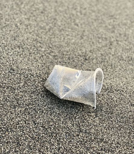 A vertical high angle shot of a plastic cup on the sandy beach - concept: soil pollution
