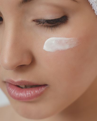 A vertical closeup shot of a female with moisturizing cream on her face - perfect for a spa concept