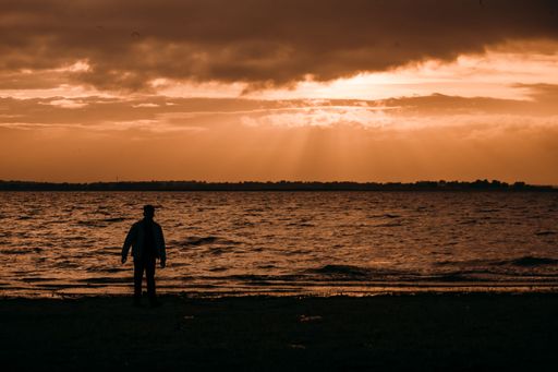 A silhouette of a man on the beach during a vibrant sunset at late evening