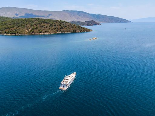 An aerial view of a big boat heading towards the open sea on a sunny day