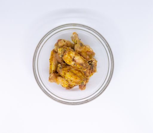 An overhead shot of delicious buffalo wings in sauce on a white table