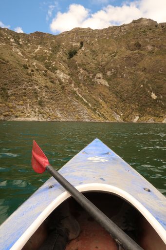 A vertical shot of kayak boat on a lake with a mountain background in Ecuador