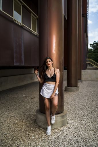 A vertical shot of young caucasian female posing while leaning on a column of a building