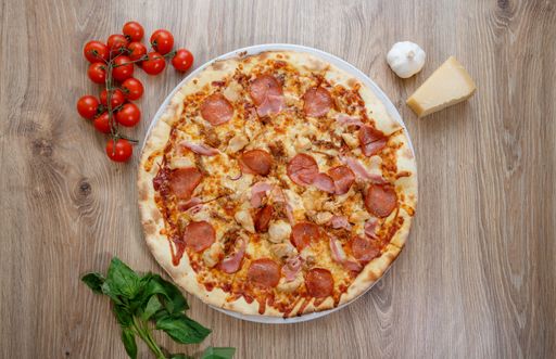 A top view of a gourmet pepperoni pizza on a wooden table with ingredients
