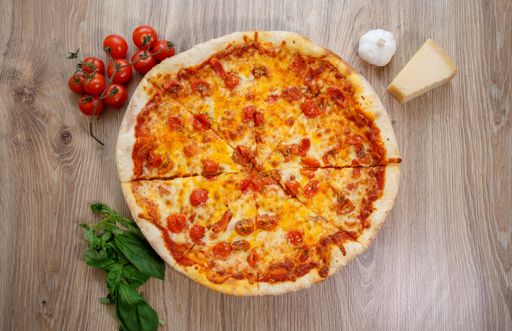 A top view of a gourmet cheese pizza on a wooden table with ingredients