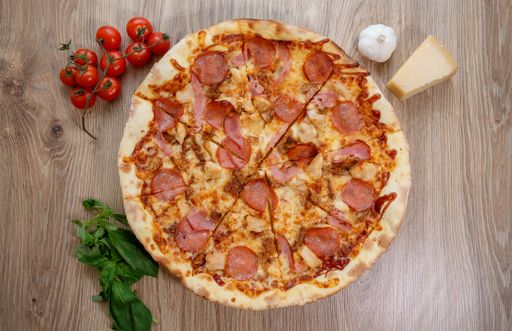 A top view of a gourmet pepperoni pizza on a wooden table with ingredients