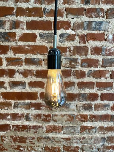 a vertical shot of a light bulb against a vintage brick wall