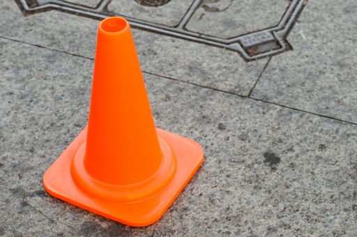 An orange traffic cone on the sidewalk
