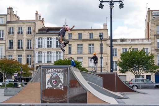 The young kids on scooters performing tricks on the ramp