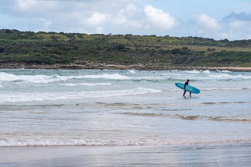 A beautiful shot of a surfer walking on low water with a surfboard