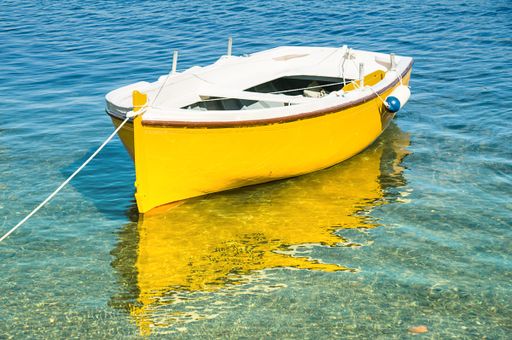 A bright yellow boat floating in clear waters on a sunny day