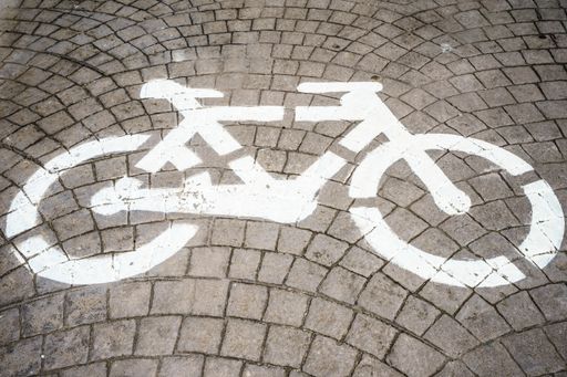 A high angle shot of a white bicycle symbol painted on a stone street