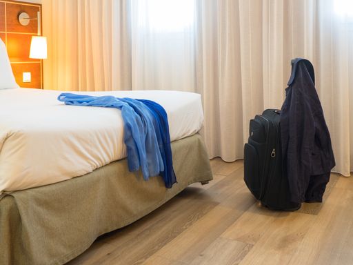 An interior of the modern hotel room with suitcase near the bed