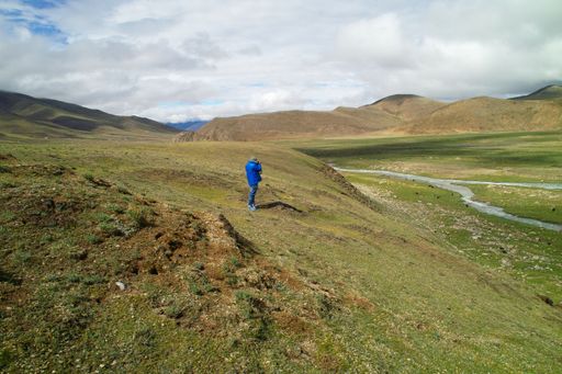 A hiker standing on the slope of the hill and enjoying the view
