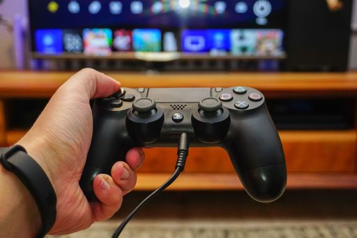 A closeup of a PS4 controller Dualshock 4 in a gamer's hand