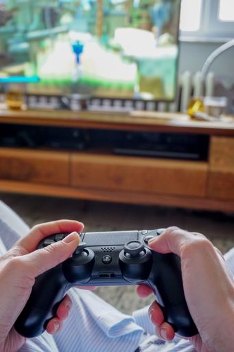A vertical top view of a person holding a Ps4 gamepad at home