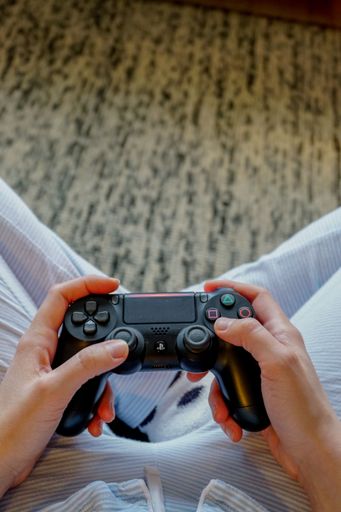 A vertical top view of a person holding a Ps4 gamepad at home