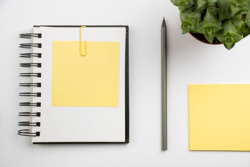A top view of a notebook and yellow sticky notes with copy space on a white surface