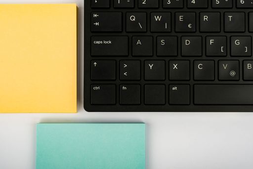 A top view of computer keyboard and colorful sticky notes with copy space