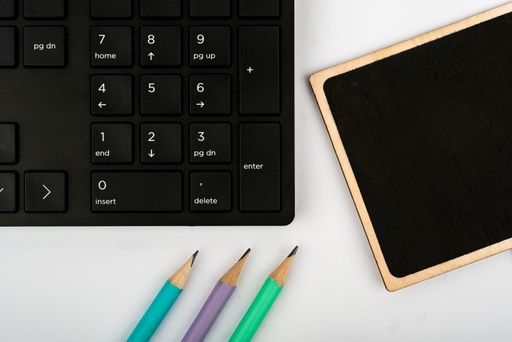 A top view of Computer Keyboard,pencils and note desk on a white background, education concept