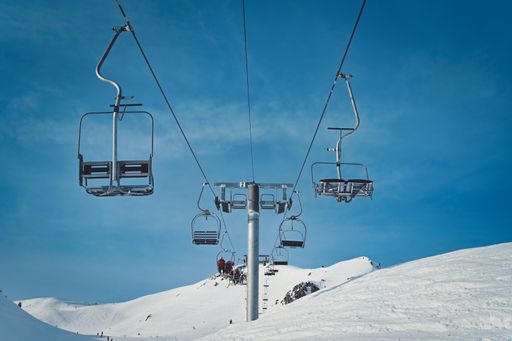 empty ski lift with  blue sky background  and snowy white mountains