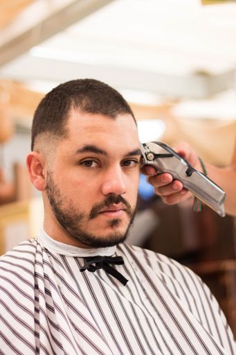 A vertical shot of a young male getting a new stylish haircut in the barbershop