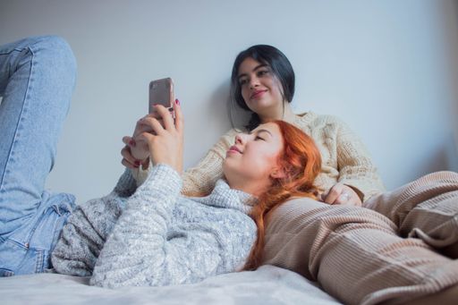 A closeup shot of two young female friends looking at a phone while relaxing indoors