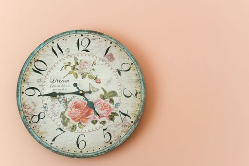 A vintage decorative floral clock on a pink wall