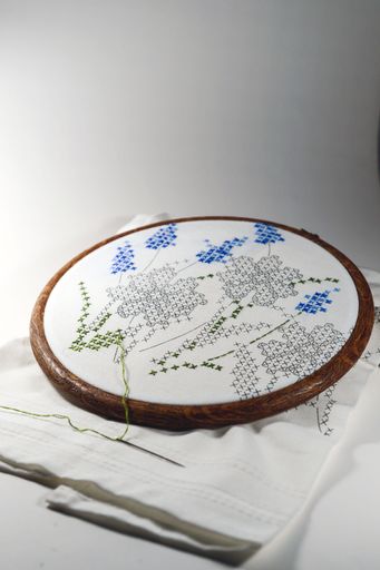 A vertical closeup shot of floral embroidery art on a round cloth