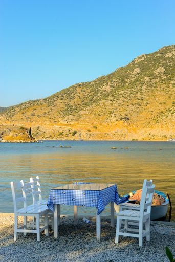 A vertical shot of a cafe table and chairs on the shore of a beach